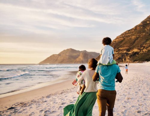 african parents with little kids bonding and strolling by ocean. little children enjoying the outdoors during their summer holidays or vacation. rear of a family walking on the beach with copy space - travel stock pictures, r