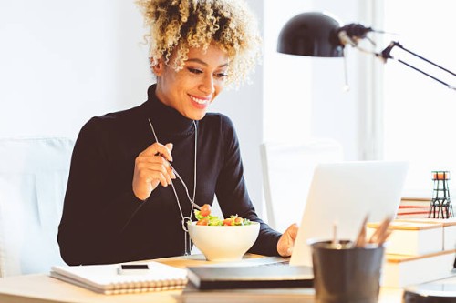 afro american young woman eating lunch at the desk - food stockfoto's en -beelden