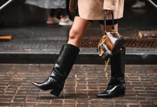 Aimee Song is seen wearing a beige coat, black leather boots and a Louis Vuitton bag outside the Tibi show during New York Fashion Week: Women's S/S...