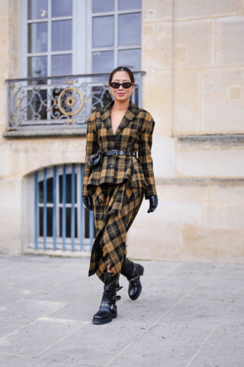 Aimee Song wears black sunglasses, dark yellow black plaid pattern Dior blazer, black leather belt, dark yellow black plaid pattern, black slouchy...