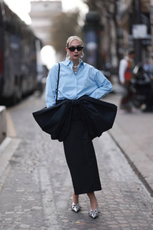 Alex Kaiser seen wearing a babyblue stripped blouse, a big black bow, black stripped long skirt and silver heels, silver necklace chains and black...