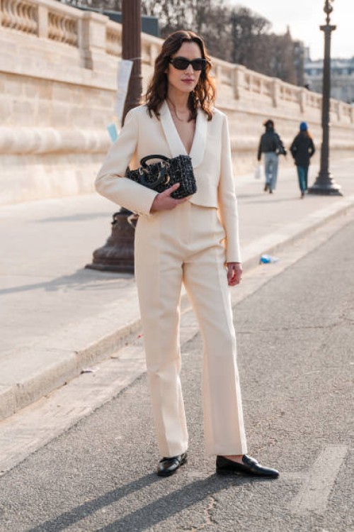 Alexa Chung wears cream suit, Dior bag, black Dior loafers, black sunglasses, outside Dior, during the Womenswear Fall/Winter 2024/2025 as part of...