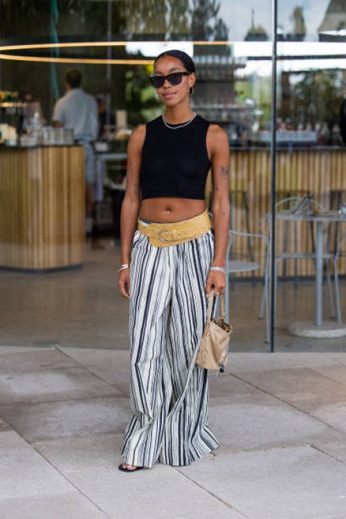 Amaka Hamelijnck wears black cropped top, striped pants, belt, beige bag outside Marimekko during day four of the Copenhagen Fashion Week SS25 on...
