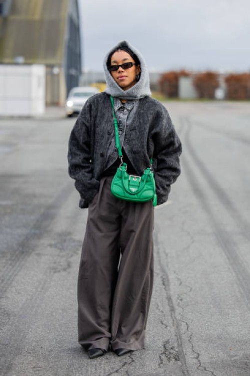 Amaka Hamelijnck wears grey balaclava, green bag, denim jeans jacket, grey wide leg pants outside Marimekko during the Copenhagen Fashion Week...