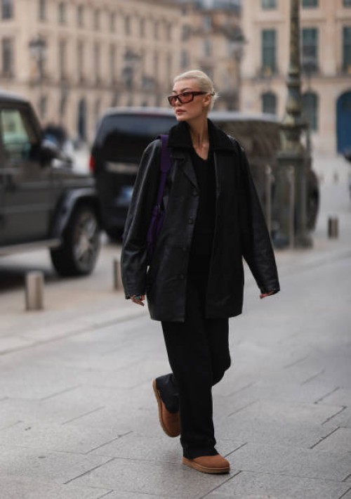 Amalie Gassmann wearing brown shades, a black leather blazer, a black fur shirt, a purple bag, black wide pants and UGG chestnut Classic Mini II Boot...