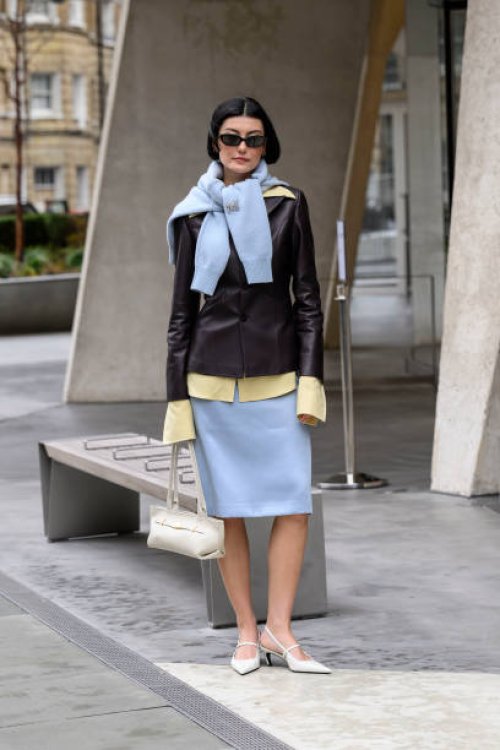 Amalie Gassmann wears Toteme shoes, DeMellier bag, Mithridate skirt, shirt, jacket and jumper and black sunglasses during London Fashion Week...