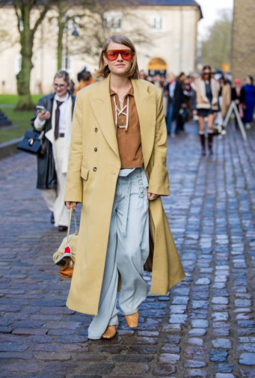 Amalie Nielsen wears beige coat, blue pants, bag, red sunglasses outside Munthe during the Copenhagen Fashion Week Autumn/Winter 2025 on January 30,...