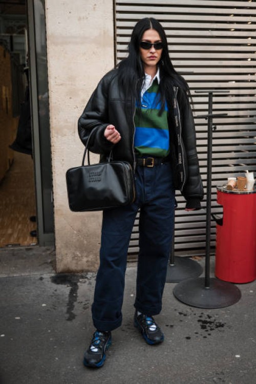 Amelia Gray Hamlin wears blue and green polo neck top, black leather jacket, blue pants, Miu Miu black. Bag, black and blue sneakers, outside...