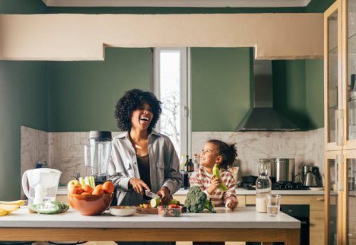 an african-american single mother preparing vegan lunch in the kitchen and smiling with her little daughter - food stock pictures, royalty-free photos & images