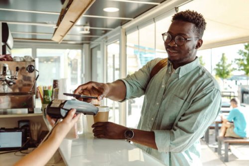 an african american young man paying at the coffee shop - coffee stock pictures, royalty-free photos & images