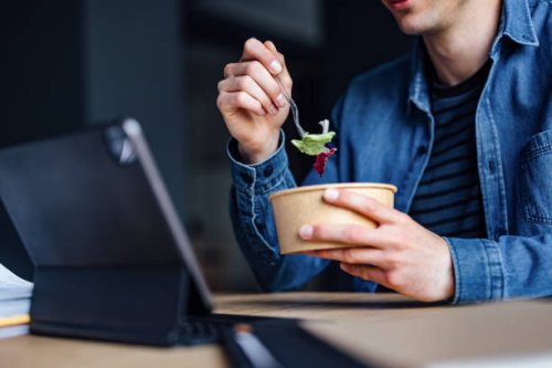 an anonymous student studying online on his digital tablet and eating lunch in the library - junk food stock pictures, royalty-free photos & images