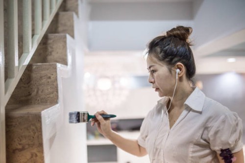 an asia chinese women listening music and painting walls using paint brush in her new house. home makeover and renovation concept. - home decoration stock pictures, royalty-free photos & images