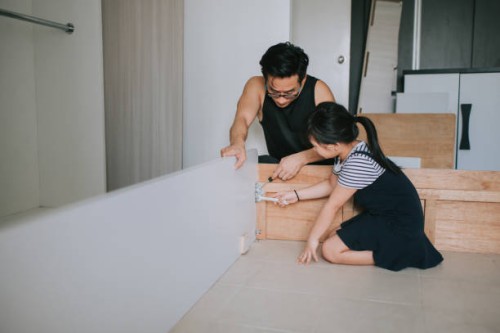an asian chinese family moving house daughter helping her father assemble bed frame - home decoration stock pictures, royalty-free photos & images