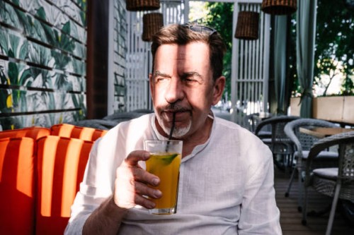 an elderly man drinks lemonade in a street cafe. - garden decoration photos et images de collection