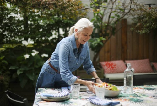 an elderly woman setting the table on her terrace - garden decoration photos et images de collection