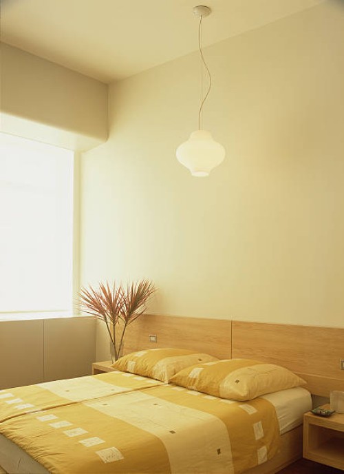 an elegant lamp is suspended from the ceiling above the bed in the bedroom - home decoration stock pictures, royalty-free photos & images