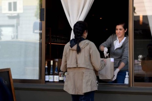 An employee for Atelier Crenn restaurant hands a takeout order to a customer through a window in San Francisco, California on April 2020, during the...