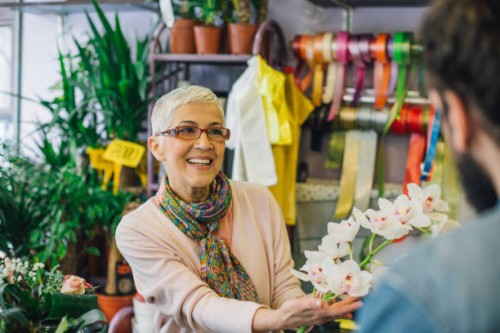 an experienced florist presenting flowers to a customer - garden decoration stock pictures, royalty-free photos & images