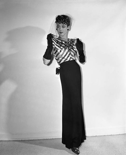 An eye-catching bodice of black and pink striped satin, embroidered with jet, tops the slim black crepe skirt of this Hattie Carnegie model. The...