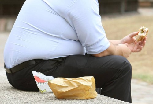 An overweight man eats fast food. GPs and other health professionals should tell people they are fat rather than obese, a health minister said today.