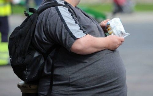 An overweight man with an obscured face eats crisps on March 29, 2009 in Cardiff, United Kingdom.
