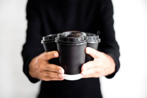 an unrecognizable man holding three disposable and black paper coffee cups with lids on - junk food stock pictures, royalty-free photos & images