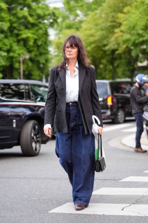 Anastasia Barbieri wears white button up long sleeve shirt, gray wool blazer, high waisted loose navy blue denim jean pants, black bag, brown boots...