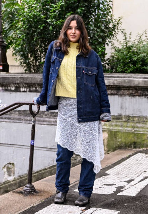 Anna Espin is seen wearing a blue jean jacket, lime green sweater, lace white skirt and blue jeans with black shoes outside the Rabanne show during...
