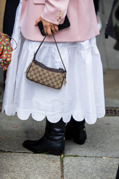 Anna Schürrle wears Gucci bag, white dress, pink blazer, black Chanel boots outside Horror Vacui during the Berlin Fashion Week SS25 on July 03, 2024...