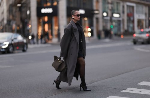 Anna Wein is seen wearing black oval sunglasses; chunky squared earrings in gold with a black stone from H&M Studio; an oversized ankle-length grey...