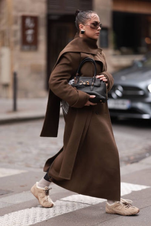 Anna Wein is seen wearing rimless oversized sunglasses with brown lenses, slim gold metal temples, and a gold metal nose bridge from Miu Miu; chunky...