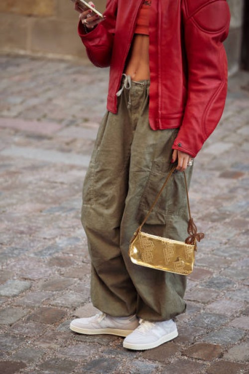 Anna Winck is wearing army green pants, white and grey New Balance sneakers, red leather jacket, golden bag during the Copenhagen Fashion Week AW24...