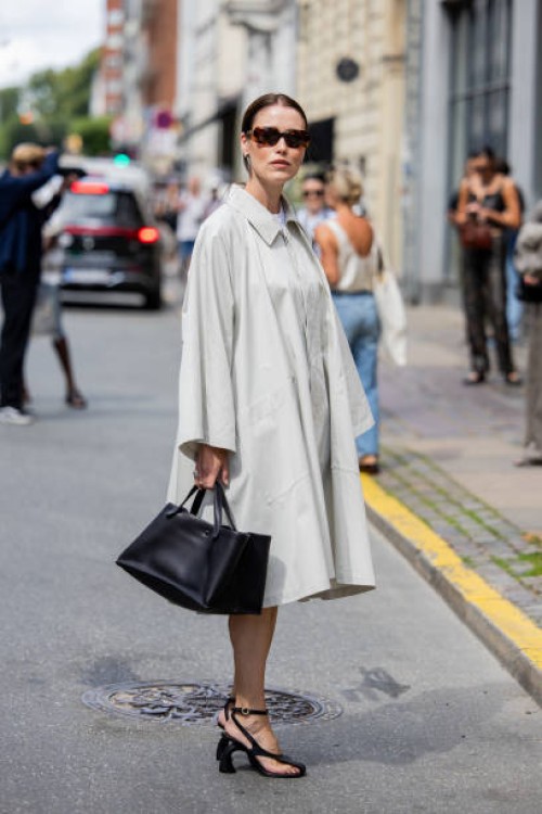 Annabel Rosendahl wears grey oversized button up dress, black bag, heeled sandals, sunglasses outside Gestuz during day four of the Copenhagen...