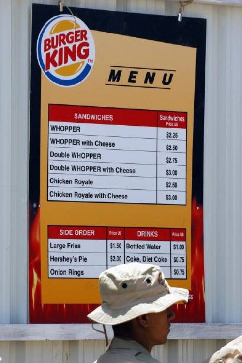 Army soldier waits in line at a Burger King take out restaurant in the army base set up at Baghdad's international airport, 14 July 2003. Soldiers...