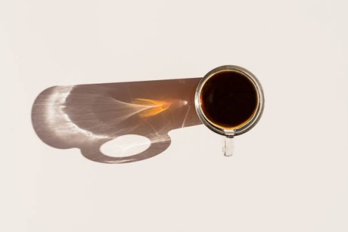 aromatic morning coffee and a long shadow from the cup. - coffee stockfoto's en -beelden