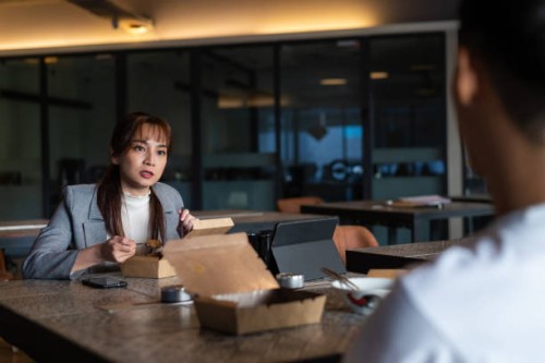 asian business woman having take away food with colleague at office lounge during lunch break - junk food stock pictures, royalty-free photos & images