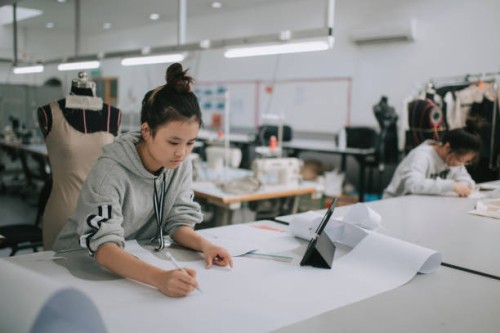 asian chinese female fashion college student writing down measurement and drawing sewing pattern doing clothing project at college workshop - fashion stock pictures, royalty-free photos & images