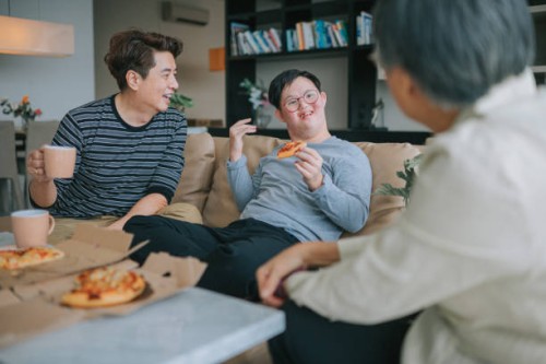 asian chinese multi generation family with down syndrome grandson enjoying pizza fast food in living room sitting on sofa during weekend - junk food stock pictures, royalty-free photos & images