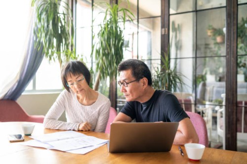 asian couple looking at blueprints of their new house - home decoration stock pictures, royalty-free photos & images