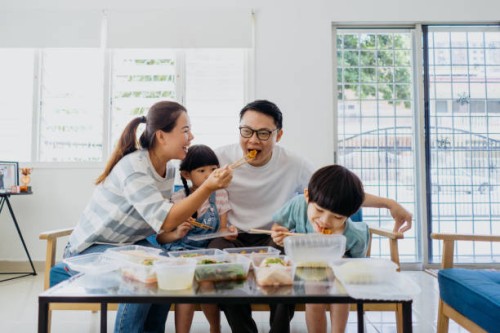 asian family having take out food in living room - junk food stock pictures, royalty-free photos & images