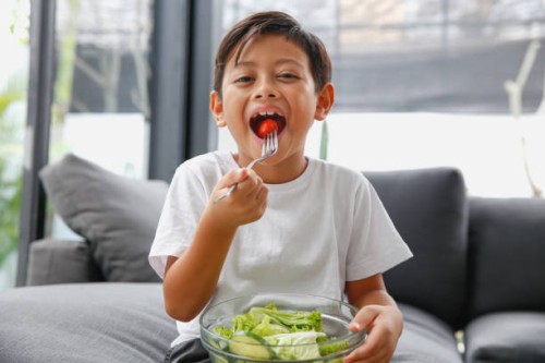 asian little boy eating healthy green salad - food stock pictures, royalty-free photos & images