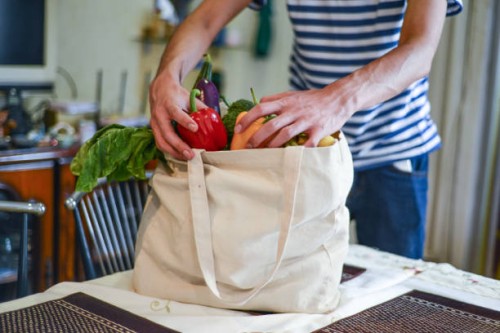 asian man unpacking groceries at kitchen island - food stock pictures, royalty-free photos & images
