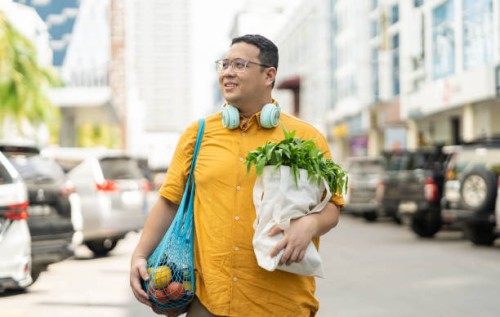 asian man walking on street with groceries on hands - food stock pictures, royalty-free photos & images