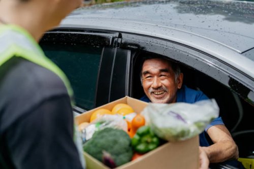 asian senior man receiving donated groceries from volunteer at drive through food bank - food stock pictures, royalty-free photos & images
