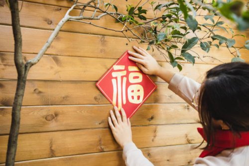 asian woman hanging chinese new year decoration (“福”) on the wall of the front/back yard - garden decoration stock pictures, royalty-free photos & images