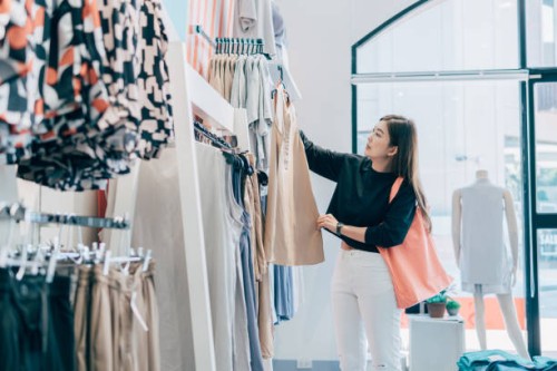 asian woman trying clothes for decision. woman looking at casual clothing while shopping in clothing store. - fashion stock pictures, royalty-free photos & images