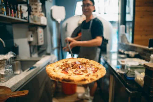 at the restaurant, a pizza chef is preparing pizza on the workstation. - junk food stock pictures, royalty-free photos & images