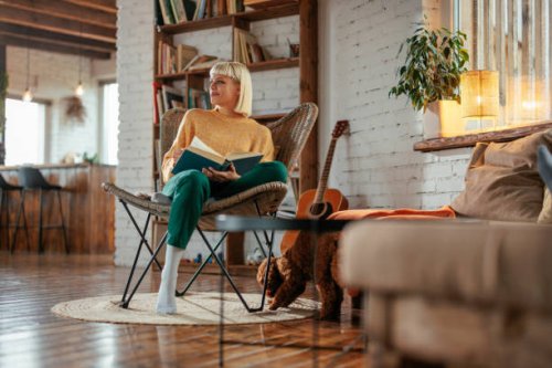 attractive young adult woman reading book in living room. - home decoration stock pictures, royalty-free photos & images