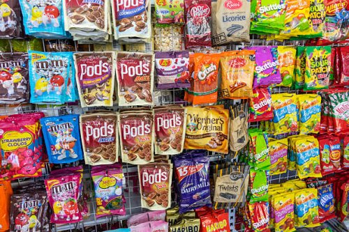 Australia, Sydney, Haymarket EzyMart convenience store snacks junk food display sale candy chocolate bags competing brands packaging.