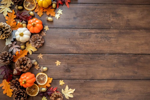 autumn modern decorated wooden table for thanksgiving or halloween with pumpkins, dried orange slices. bright colorful with gold details. overhead view of gourds, dry leaves, shot on rustic wooden table. thanksgiving backgrou